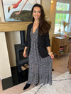 Black blazer with ruched sleeves worn open over a black-and-white patterned dress.