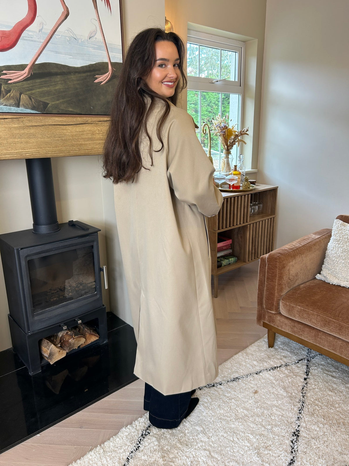 Taupe longline trench coat shown from the back, with a collared neckline and long sleeves.
