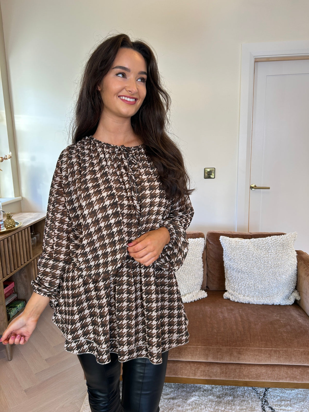 Brown and cream checked tunic with a loose silhouette and long balloon sleeves, shown worn with black trousers.